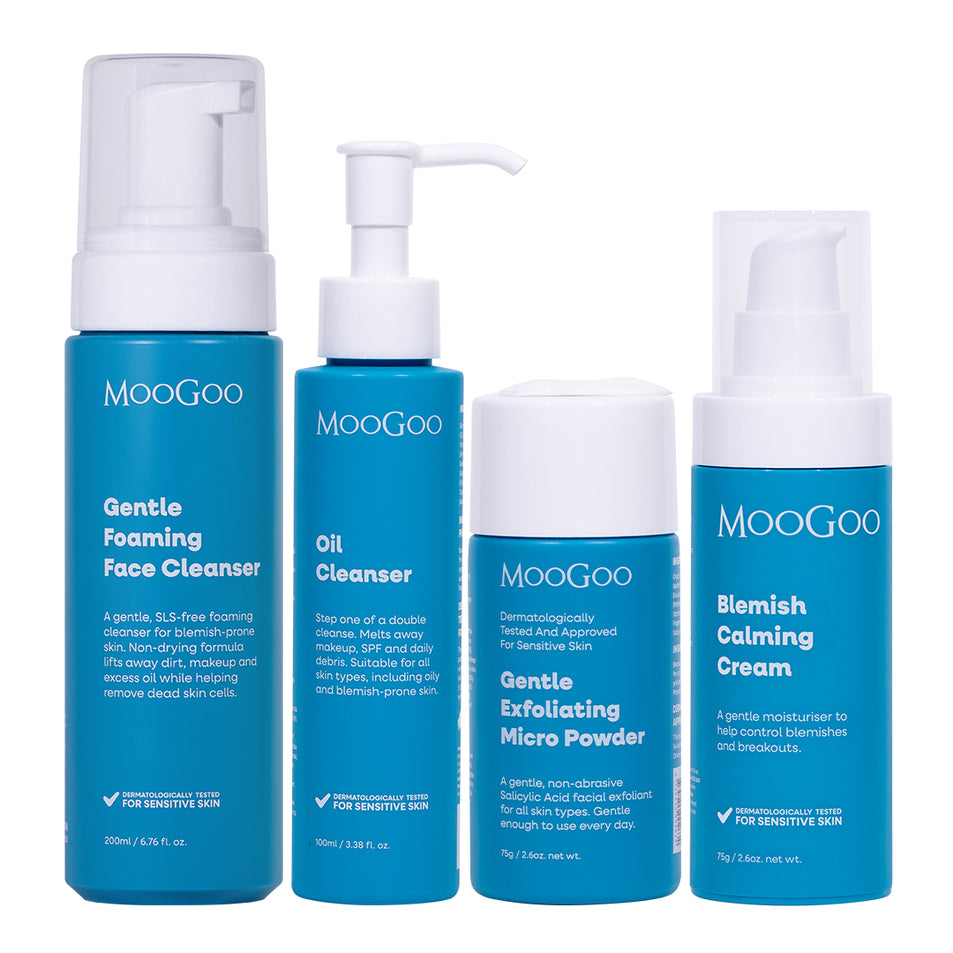 Four MooGoo skincare products in blue and white packaging, including Gentle Foaming Face Cleanser, Oil Cleanser, Exfoliating Micro Powder, and Blemish Calming Cream, arranged against a plain white background.